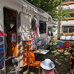 Kind mit Sonnenhut vor geöffneten Streetjumper-Mobil