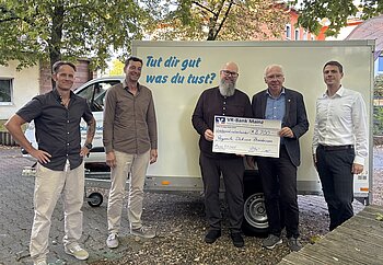 Fünf Personen stehen vor neuem Anhänger zur offiziellen Checkübergabe
