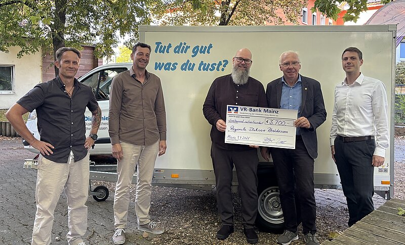 Fünf Personen stehen vor neuem Anhänger zur offiziellen Checkübergabe