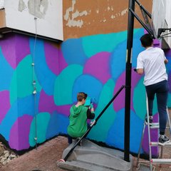 Zwei Personen verschönern Außenwand mit Farbe