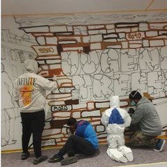 Vier Jugendliche besprühen Wand im Jugendtreff