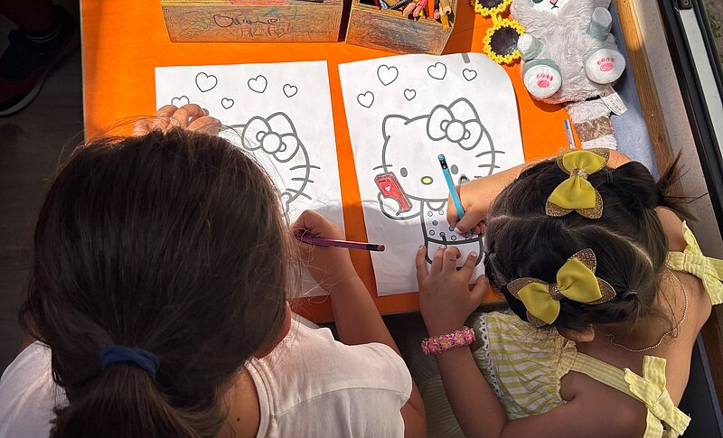 Zwei Kinder malen mit Buntstiften Vorlagen aus