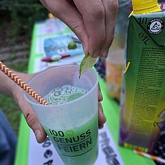 Hand hält Becher mit grünem alkoholfreien Drink