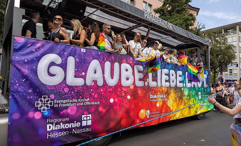 Bunter Wagen mit Regenbogenfarben und dem Schriftzug „Glaube. Liebe. Leben.“ beim CSD in Frankfurt