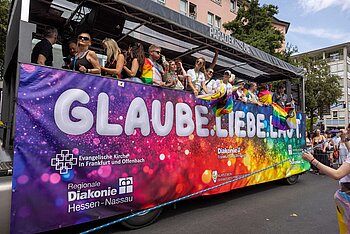 Bunter Wagen mit Regenbogenfarben und dem Schriftzug „Glaube. Liebe. Leben.“ beim CSD in Frankfurt