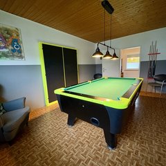 Blick in Raum mit von oben angestrahltem Billiardtisch