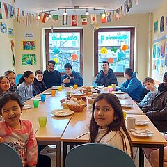 Gut gelaunte Kinder sitzen um großen gedeckten Tisch