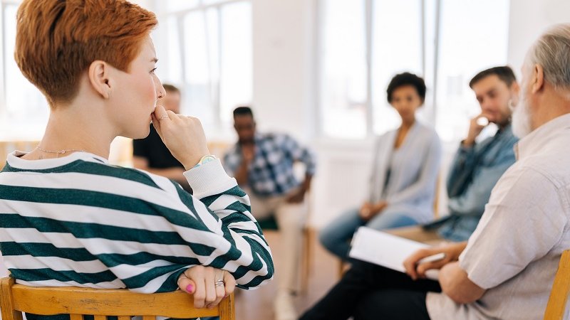Erwachsene Menschen sitzen im Stuhlkreis 