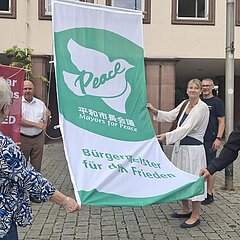 Menschen halten die Fahne beim Hissen vor dem Rathaus