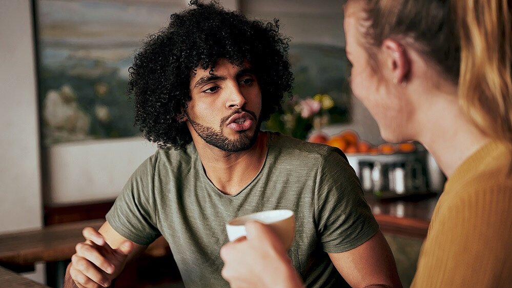 Mann und Frau im Gespräch mit Kaffeetassen