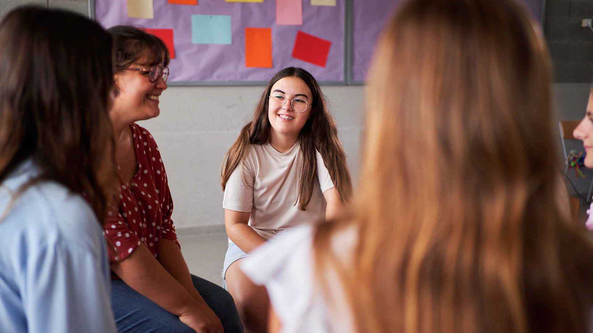 Mehrere Jugendliche und eine erwachsene Bezugspersonen in einer begleiteten Gesprächssituation.
